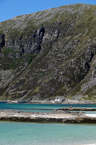 Solitary Cabin on Rocky Coastline with Turquoise Water