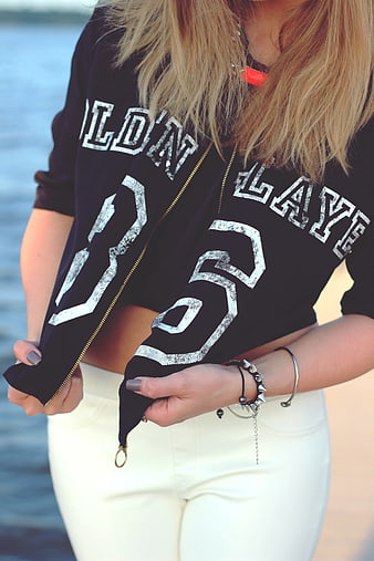 Woman wearing black varsity jacket with white text