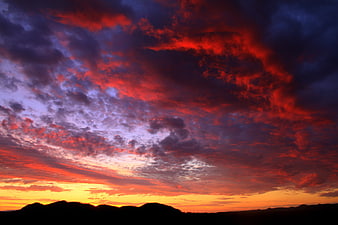 Dramatic red and purple sunset clouds over silhouetted mountains