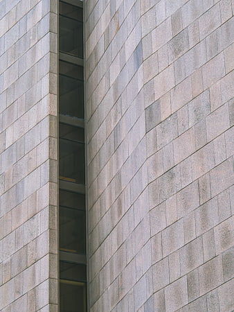 Modern gray stone building facade with vertical window slit