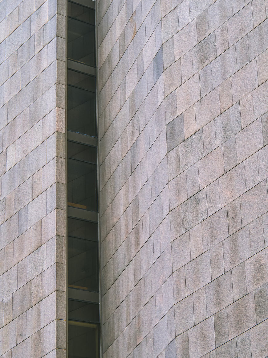 Modern gray stone building facade with vertical window slit