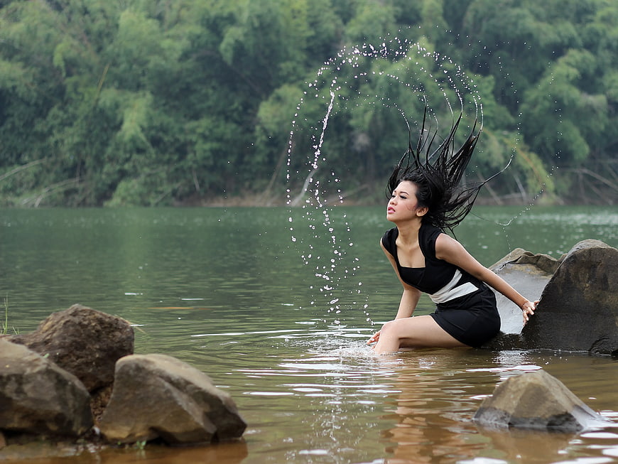 Woman splashing water in river with flying hair