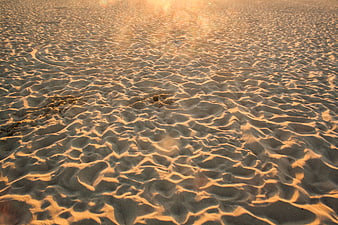 Golden hour ripples on sandy beach texture background
