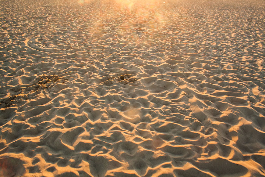 Golden hour ripples on sandy beach texture background