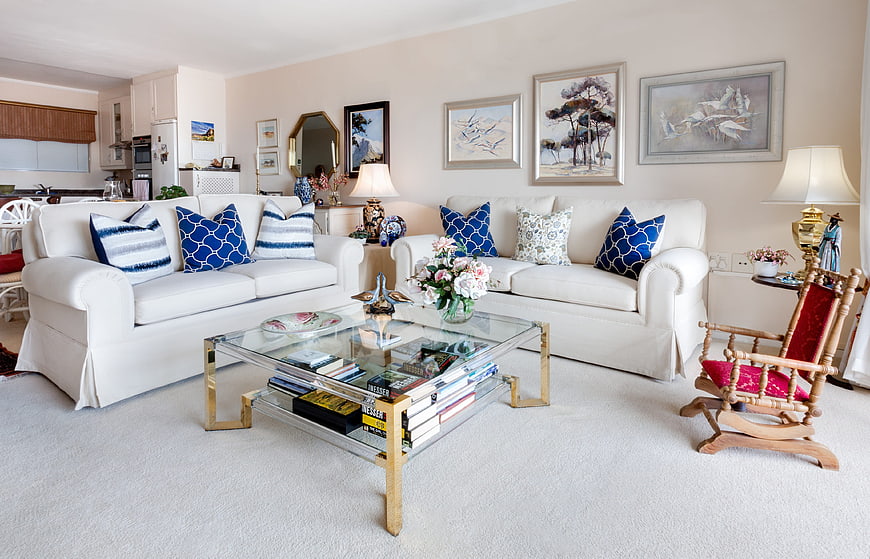Bright White Living Room With Blue Accent Pillows And Glass Coffee Table