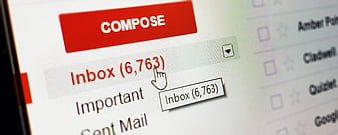 Close-up of computer screen showing full email inbox with compose button