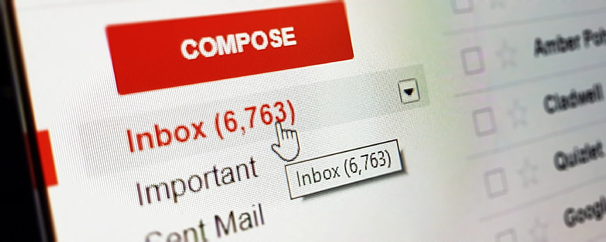 Close-up of computer screen showing full email inbox with compose button