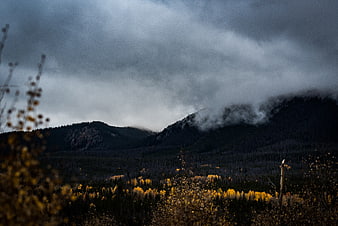 Dramatic Autumn Mountain Landscape with Golden Trees and Stormy Sky