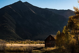 Rustic wooden cabin in autumn valley with mountain backdrop