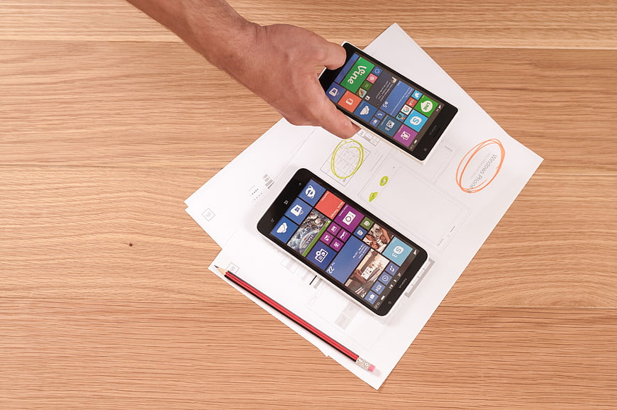 Top view of smartphones on design sketches and wooden desk