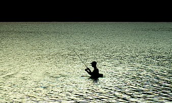 Silhouette of Man Fishing in Lake at Sunset