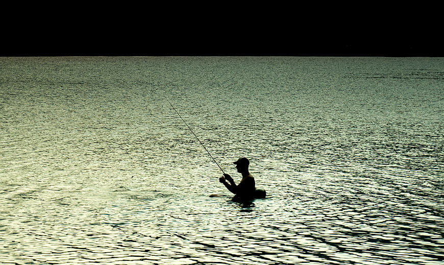 Silhouette of Man Fishing in Lake at Sunset