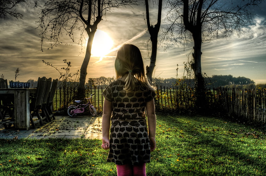 Little Girl Standing in Garden at Sunset