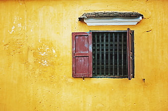 Vintage red window shutters on textured yellow wall