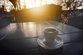 White coffee cup on wooden table with golden sunset background
