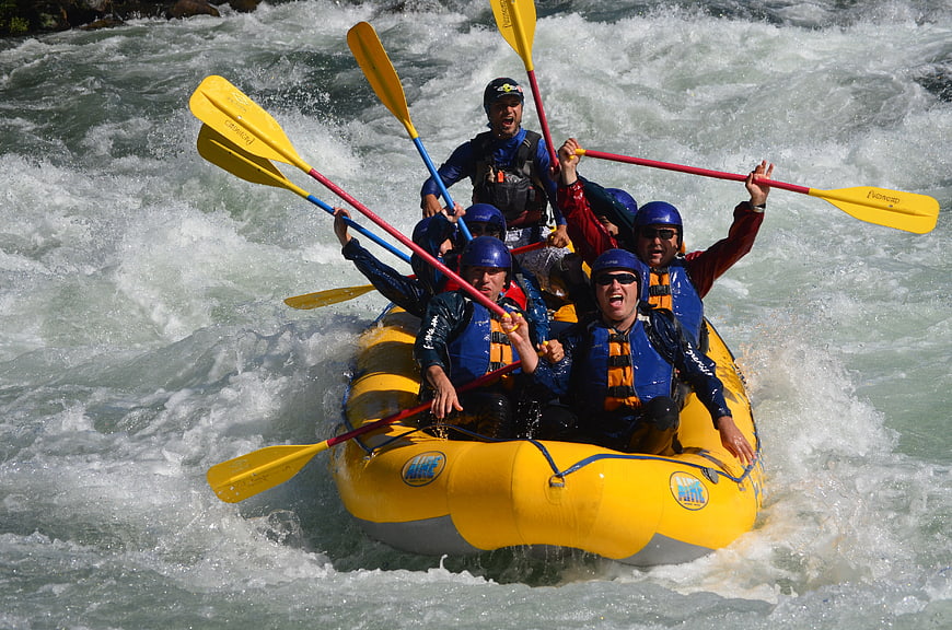 Group of people white water rafting in yellow raft