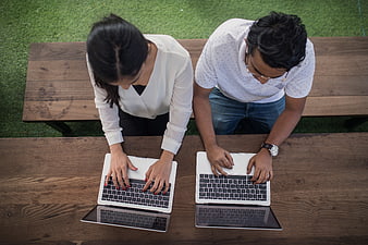 Top view of business colleagues working on laptops at wooden table