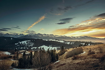 Snowy Mountain Range at Sunset with Golden Sky