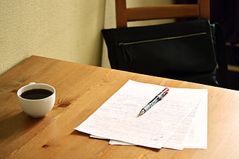 Coffee cup and handwritten papers on wooden table