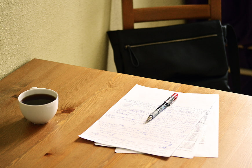 Coffee cup and handwritten papers on wooden table