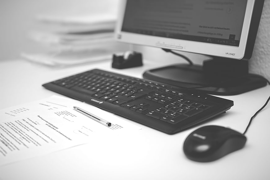 Black and White Office Desk with Computer, Keyboard, and Documents