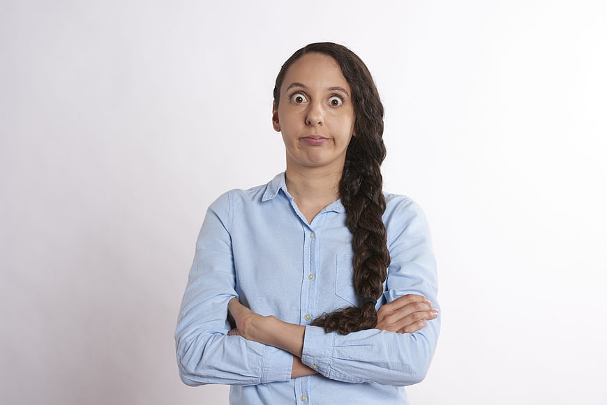 Woman with crossed arms and shocked expression on white background