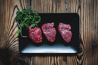 Raw Beef Steaks on Black Slate with Parsley