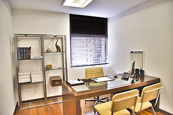 Modern office interior with desk, bookshelf, and window blinds