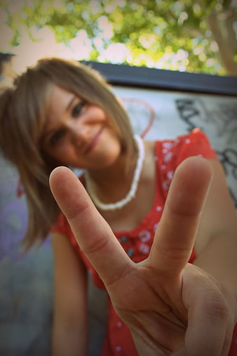 Young Woman Making Peace Sign with Blurred Background