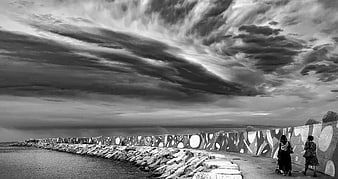 Dramatic black and white clouds over graffiti sea wall