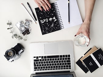 Flat lay workspace with laptop, camera, notebook, and coffee