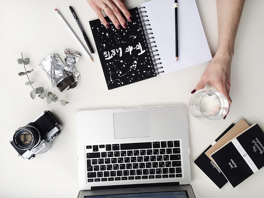 Flat lay workspace with laptop, camera, notebook, and coffee