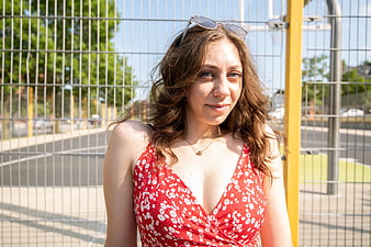 Young woman in red floral dress smiling outdoors