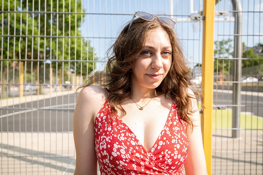 Young woman in red floral dress smiling outdoors
