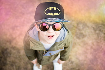 High angle portrait of smiling boy wearing Batman hat and sunglasses