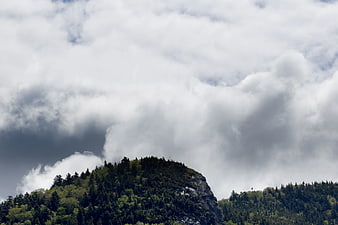 Dramatic Clouds Over Forested Mountain Peak