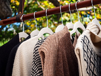 Knit Sweaters Hanging on Wooden Rack Outdoors