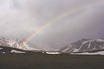 Rainbow over Snowy Mountain Landscape with Campsite