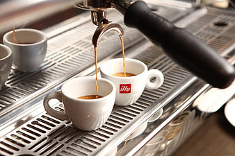 Espresso pouring into white cups from machine