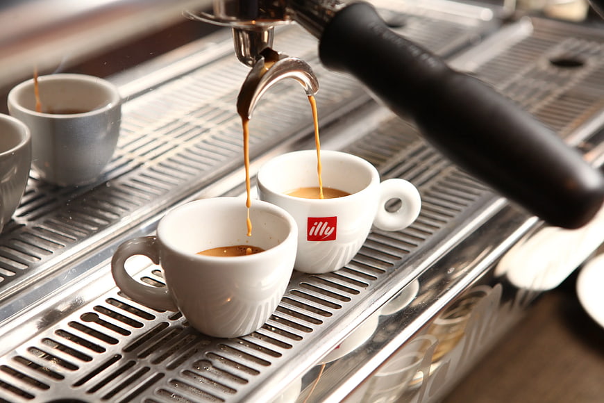 Espresso pouring into white cups from machine