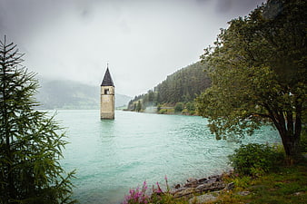 Submerged Church Tower in Alpine Lake with Forested Hills