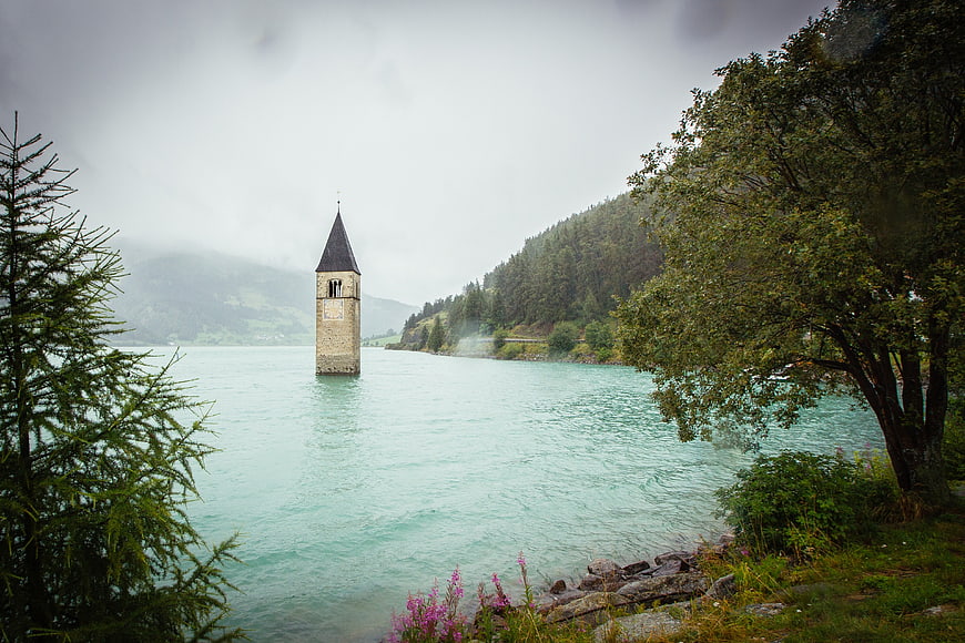 Submerged Church Tower in Alpine Lake with Forested Hills