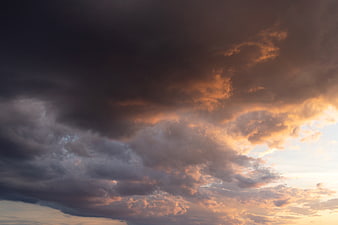 Dramatic sunset clouds with golden light breaking through dark stormy sky