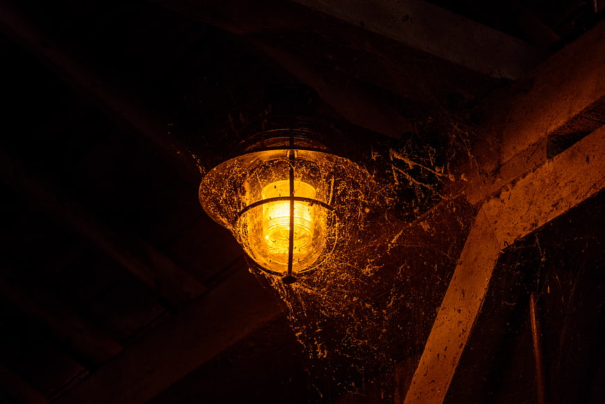 Dusty vintage lantern with spider webs in dark barn
