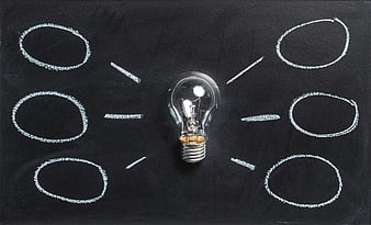 Light bulb on blackboard with chalk circles and rays