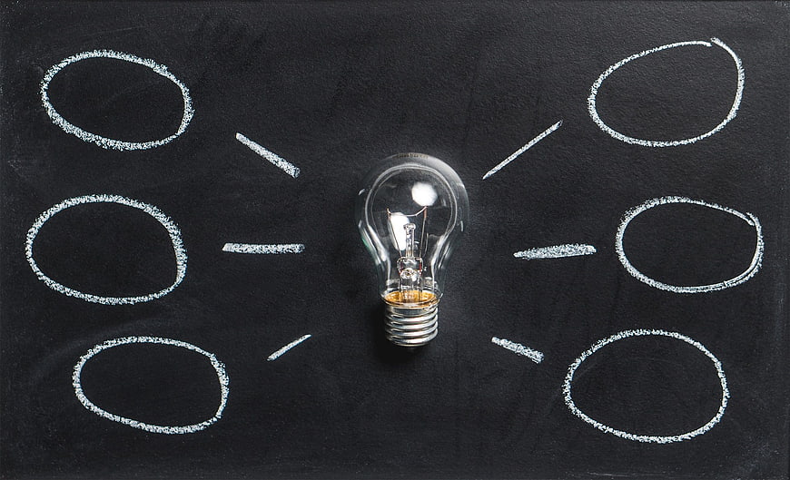 Light bulb on blackboard with chalk circles and rays