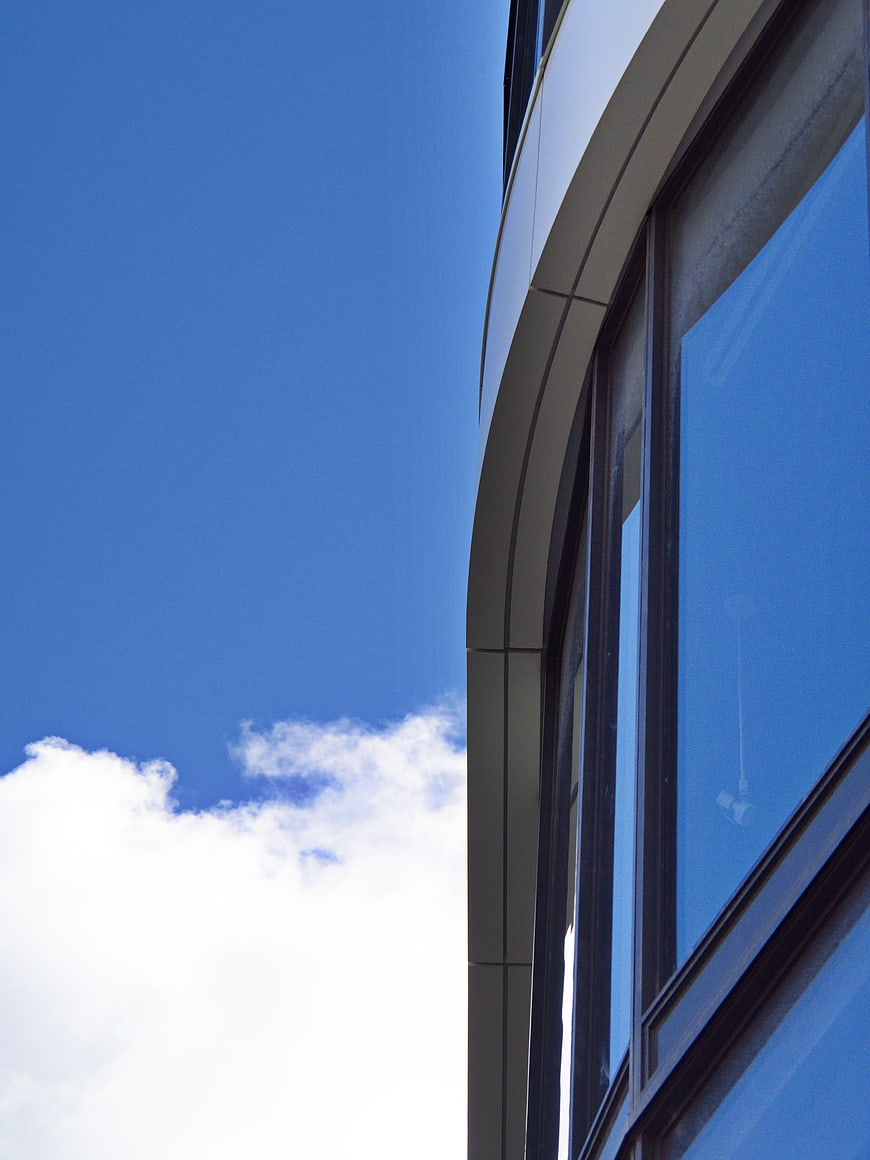Modern curved building facade against blue sky
