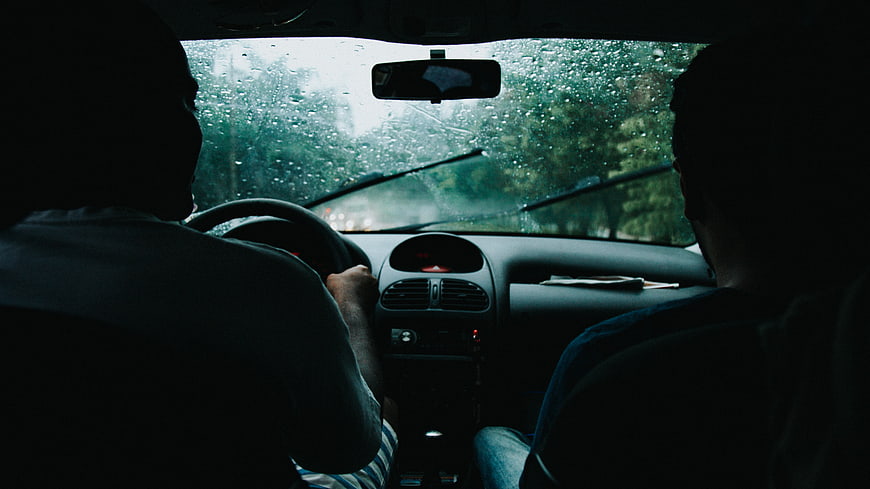 Silhouettes of Two Men Driving in Rainy Car Interior