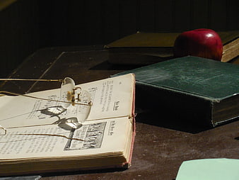 Vintage Glasses on Open Book with Apple and Old Books