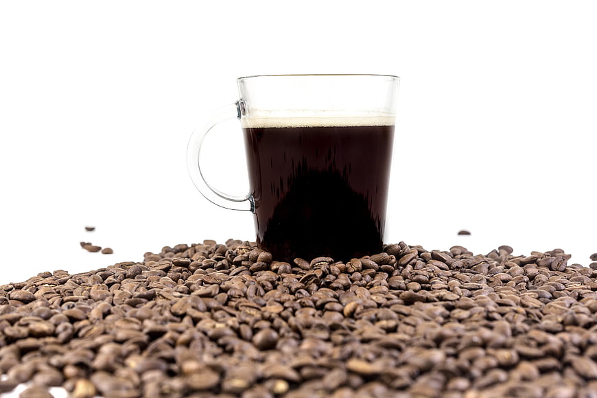 Glass Cup of Black Coffee Surrounded by Roasted Coffee Beans
